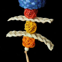 Load image into Gallery viewer, Shreddable bird toy made with a giant bamboo ball filled with crinkle paper nestled inside a brightly colored woven bamboo basket with corn husk braids and mini vine balls trailing underneath. Strung on paper rope. 
